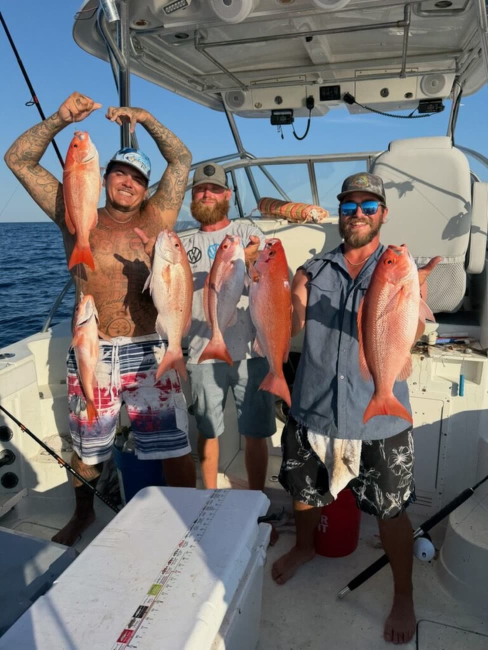 Three smiling anglers holding up a limit of red snapper and vermilion snapper under the hardtop